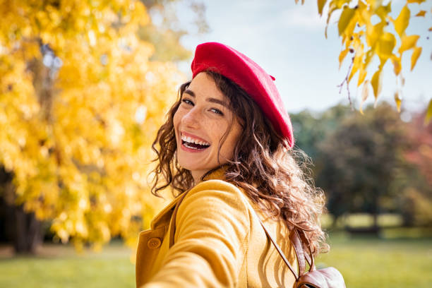 秋の日に後ろを見て笑顔の幸せな女性 - autumn women smiling leaf ストックフォトと画像