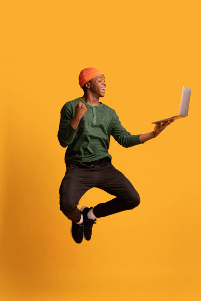istock Online Win. Excited Happy Black Guy Jumping Up With Laptop Computer 1326419841