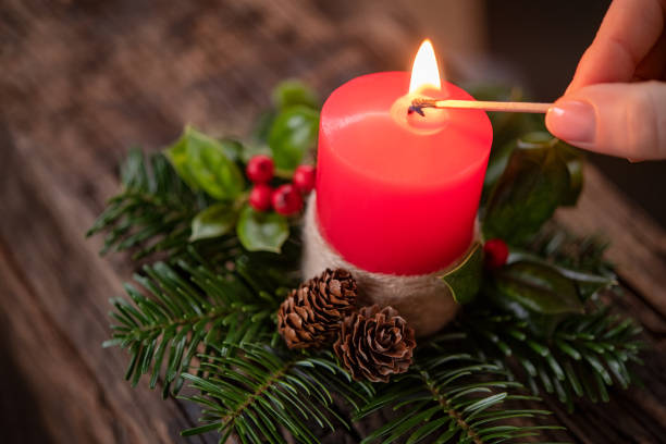 istock Woman lighting red christmas candle 1326420576