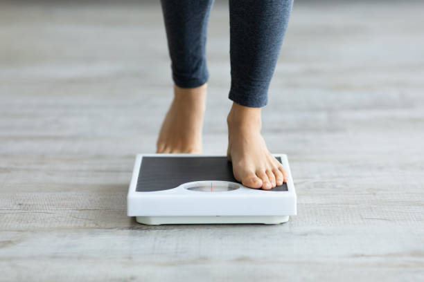 Unrecognizable young Indian woman stepping on scales to measure her weight at home, closeup of feet Unrecognizable young Indian woman stepping on scales to measure her weight at home, closeup of feet. Cropped view of millennial lady checking result of her slimming diet. Healthy living concept chubby arab stock pictures, royalty-free photos & images