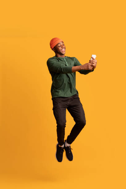 istock Cheerful African American Guy Using Modern Smartphone While Jumping In Air 1326421864