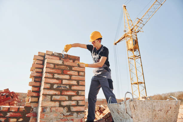 istock Installing brick wall. Construction worker in uniform and safety equipment have job on building 1326422073