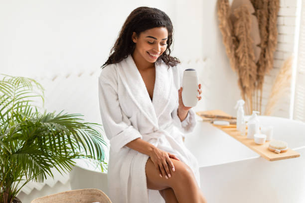 black lady holding duschgel sitzend auf badewanne im badezimmer - wellness products stock-fotos und bilder