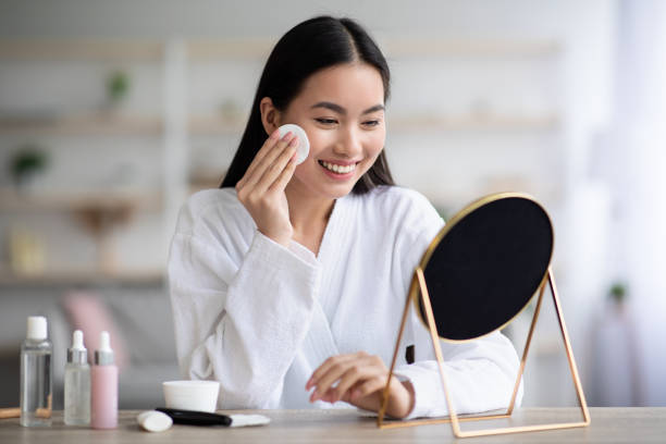 hermosa mujer asiática limpiando su cara con tóner - facial cleanser fotografías e imágenes de stock