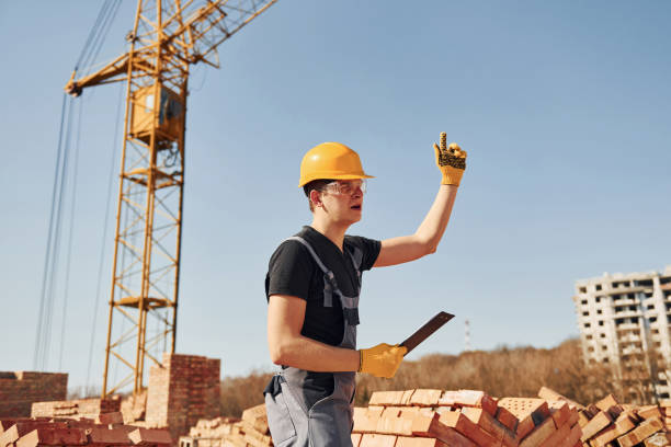 istock Shows gestures and talks. Construction worker in uniform and safety equipment have job on building 1326422273