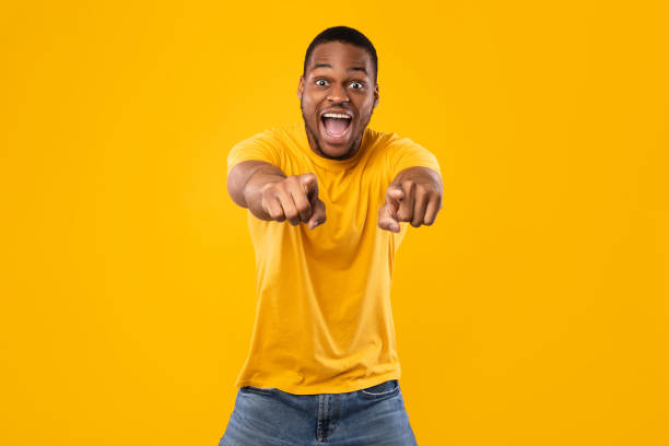 istock Emotional Black Guy Pointing Fingers At Camera Over Yellow Background 1326422324