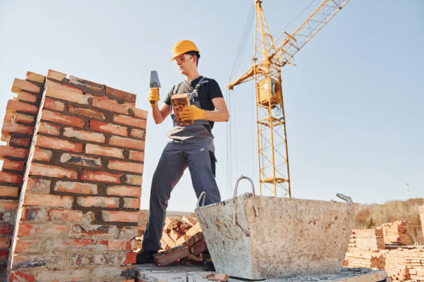 istock Installing brick wall. Construction worker in uniform and safety equipment have job on building 1326422483
