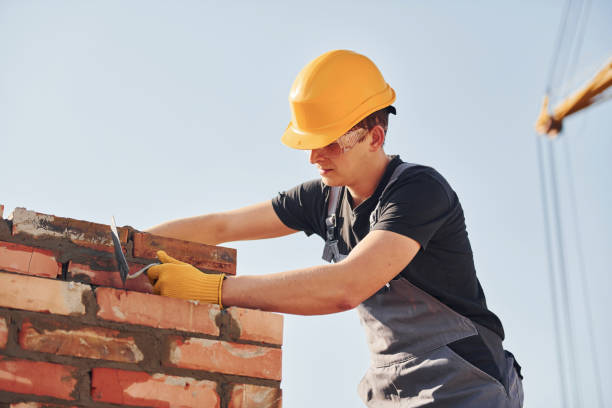 istock Installing brick wall. Construction worker in uniform and safety equipment have job on building 1326423597