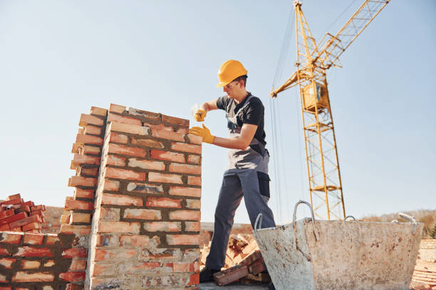 istock Installing brick wall. Construction worker in uniform and safety equipment have job on building 1326423661