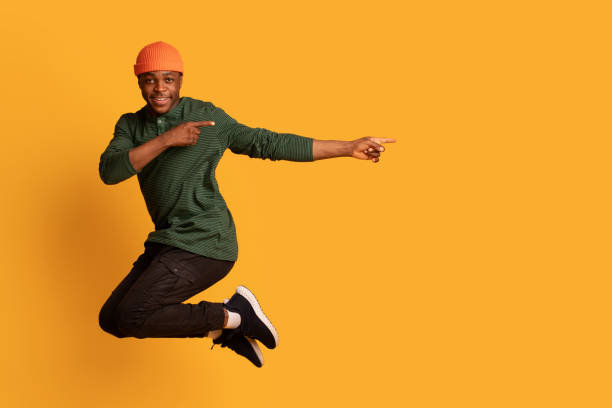 istock Look At This. Cherful african guy pointing aside while jumping in air 1326425109