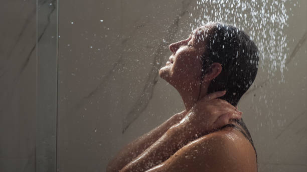istock young woman runs hands on face standing under shower water 1326427342