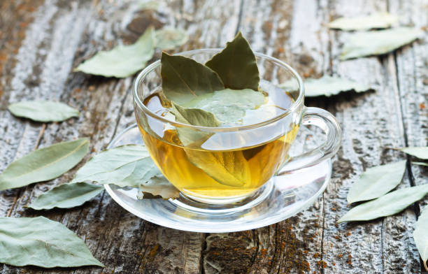 чашка натурального лаврового листа травяного чая на деревянном столе - bay leaf стоковые фото и изображения