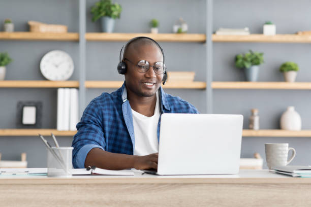 istock Hotline support service. African american male call center operator in headset working with laptop computer at home 1326427813