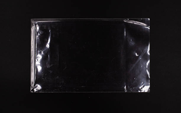transparent versiegelte kunststoffhülle auf schwarzem hintergrund, einweg-glänzende polyethylen-tasche - filmindustrie grafiken stock-fotos und bilder