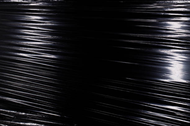 Texture of a stretched plastic film on a black background, food rumpled cellophane wrap Texture of a stretched plastic film on a black background, food rumpled cellophane wrap polythene photos stock pictures, royalty-free photos & images