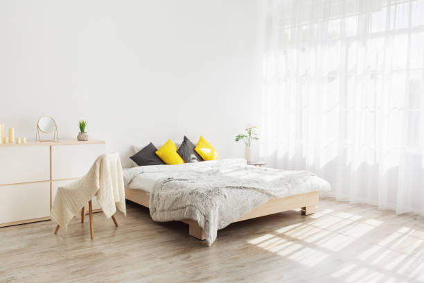istock Cozy, feminine bedroom with throw pillows and plants at white blank wall 1326428990