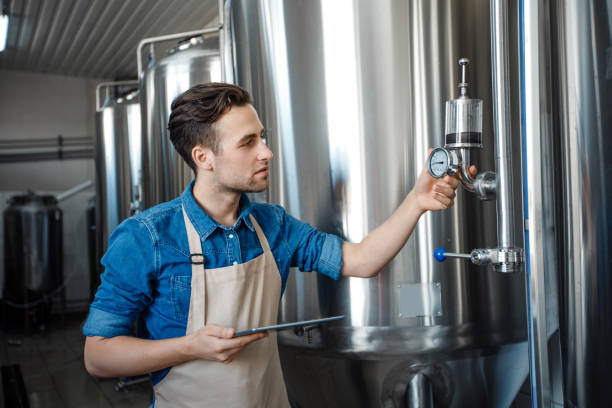 istock Brewery worker checking fermentation process in steel vat and look at notepad at plant 1326429439