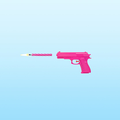 Pink gun with birthday candle on blue pastel background . Minimal party concept.