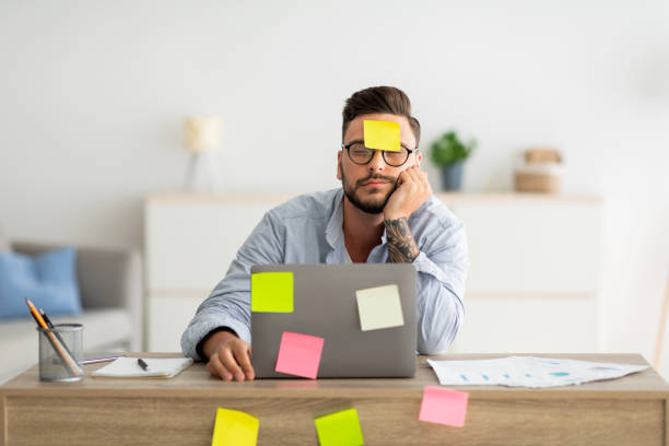 un sacco di concetto di lavoro. libero professionista stanco che dorme sul posto di lavoro con adesivi su fronte e computer - distracted foto e immagini stock