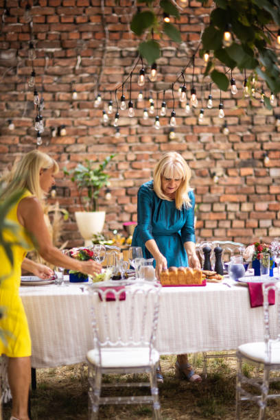 istock Two female friends preparing dining table for dinner party at backyard 1326435588