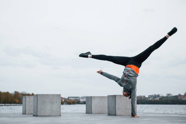 joven deportista haciendo acrobacias de parkour al aire libre cerca del lago durante el día - carrera urbana libre fotografías e imágenes de stock