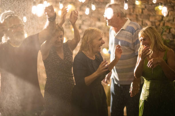istock Happy senior friends having a best time in life on party at backyard while it's raining 1326439308
