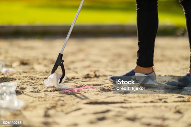 Closeup Up Of Volunteer Picking Up Garbage With Grabber At Beach Stock Photo - Download Image Now