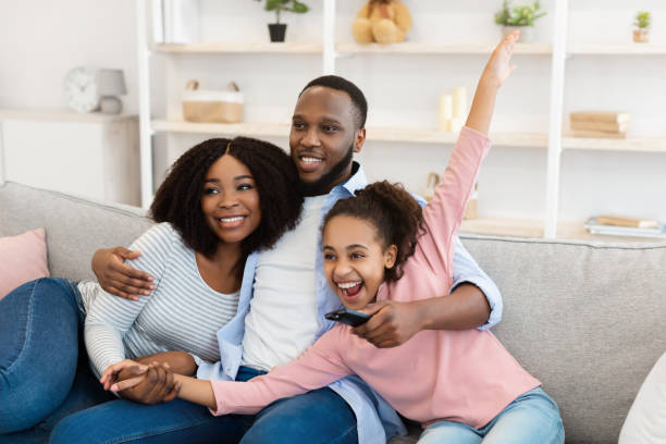 istock Happy young family watching television sitting on sofa 1326442257