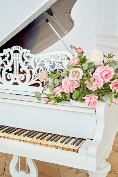 istock White grand piano with rose flowers in white classic interior, copy space 1326443608