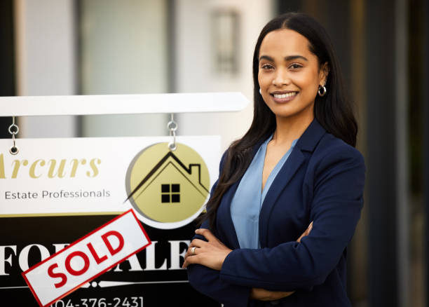 Cropped portrait of an attractive young real estate agent standing with her arms crossed next to a sold sign outside of a recently sold home Let me find the perfect home for you estate agent stock pictures, royalty-free photos & images