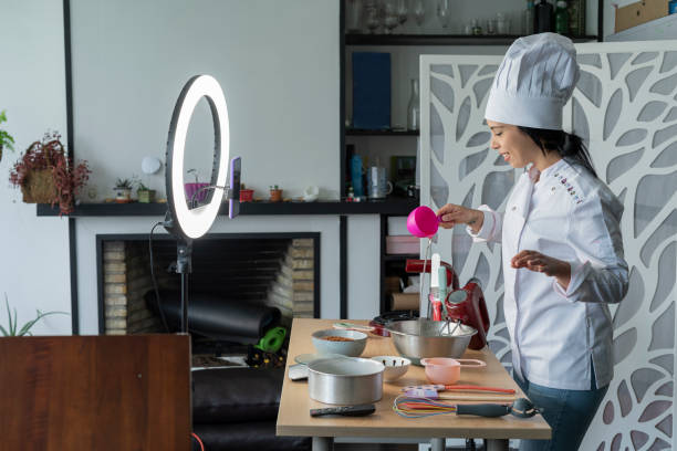 Female influencer chef speaks to her followers while doing a live show teaching how to prepare a cake using her light ring and her uniform