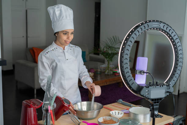 Female influencer chef speaks to her followers while doing a live show teaching how to prepare a cake using her light ring and her uniform