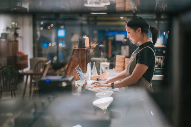 asiatische chinesische weibliche barista mit laptop beim abendessen in der café-bar-theke genießen - kantinenfrau stock-fotos und bilder