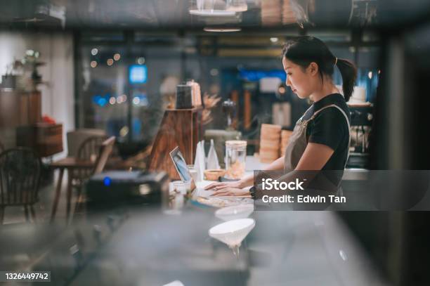 Asian Chinese Female Barista Using Laptop While Enjoying Dinner At Coffee Shop Bar Counter Stock Photo - Download Image Now