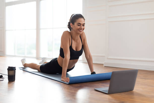 istock Young woman stretching back on mat with pc 1326450150
