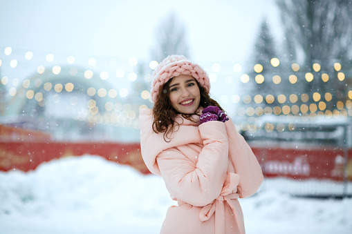 Winter portrait of romantic brunette young woman wearing warm trendy outfit, walking at the Christmas fair in Kiev. Empty space