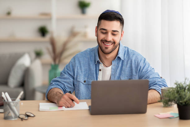 istock Smiling israeli man working on laptop at home 1326451146