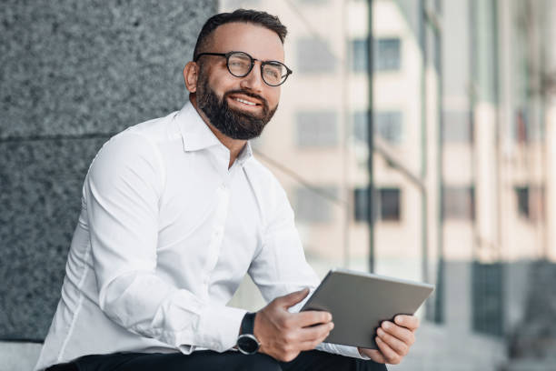 istock Confident middle-aged businessman working on tablet outdoors, sitting near modern office center, copy space 1326451166