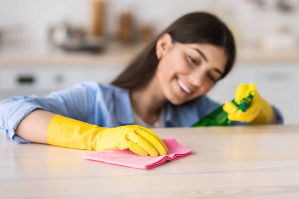 istock Cheerful young woman cleaning table with cloth 1326451195