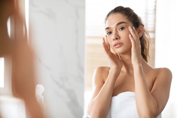 istock Female Touching Face Looking At Reflection In Mirror In Bathroom 1326451627