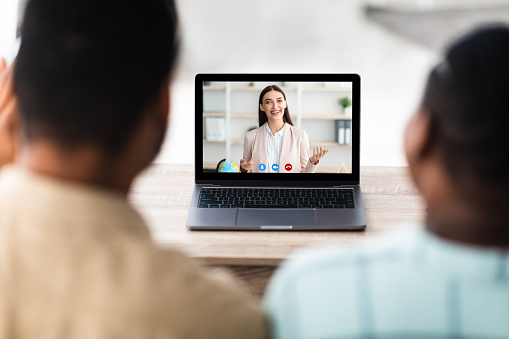 Online Consultation Concept. Rear View Of African American Couple Consulting Via Video Call On Laptop Talking With Business Consultant Or Lawyer Indoor. Modern Remote Communication Concept