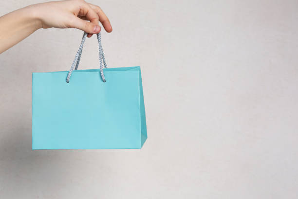 istock Female hand holding small package with a gift over a grey background. Empty space 1326452604