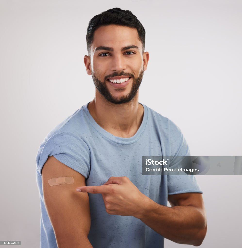 Shot of a handsome young man sitting alone in the studio after getting vaccinated Did you see what I did? Vaccination Stock Photo