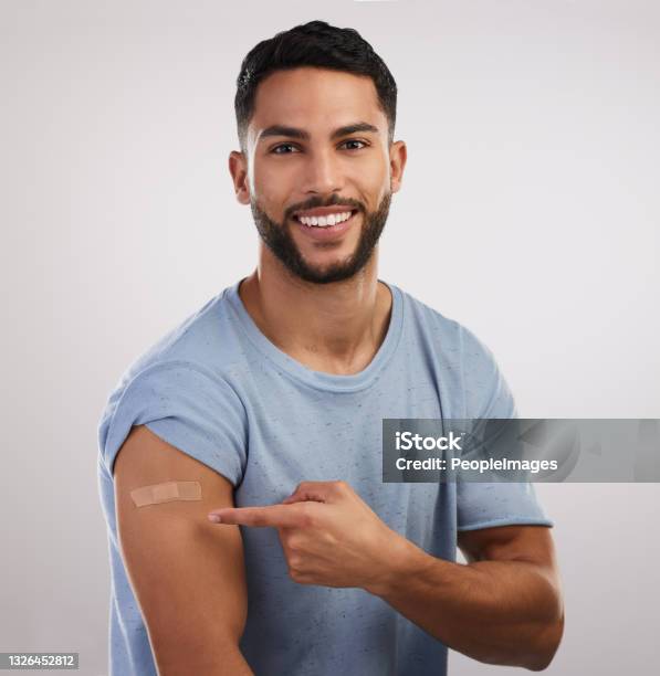 Shot Of A Handsome Young Man Sitting Alone In The Studio After Getting Vaccinated Stock Photo - Download Image Now