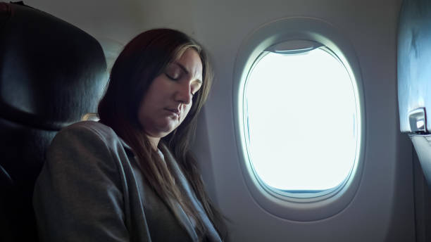 istock Brunette woman sleeping while sitting in an uncomfortable position on the plane 1326456612