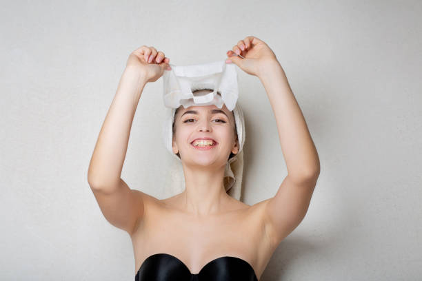 istock Smiling woman takes off sheet face mask 1326457142