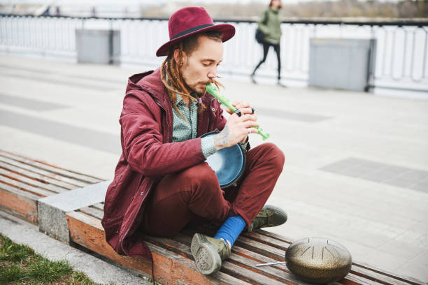 Concentrated street musician doing improvisation with musical instruments, being deep in thoughts