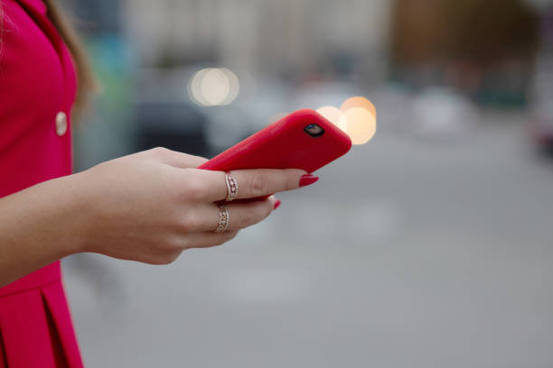 Young woman using smart phone in red case at the blur light background. Empty space