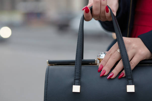 istock Female hand with beautiful red manicure opening black leather purse. Empty space 1326460311