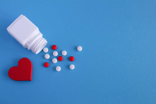 istock White,red pills and heart on the blue  background. Top view. 1326461122